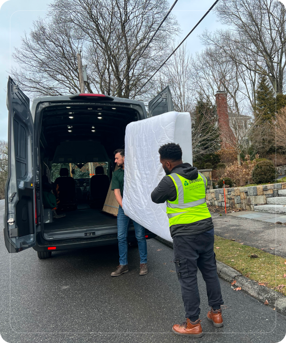 Grunber team loading an old mattress into the junk removal truck