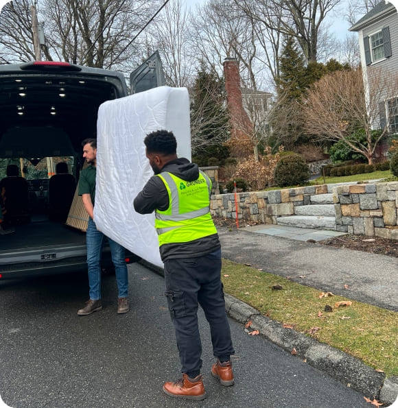 Grunber team loading an old mattress into the junk removal truck